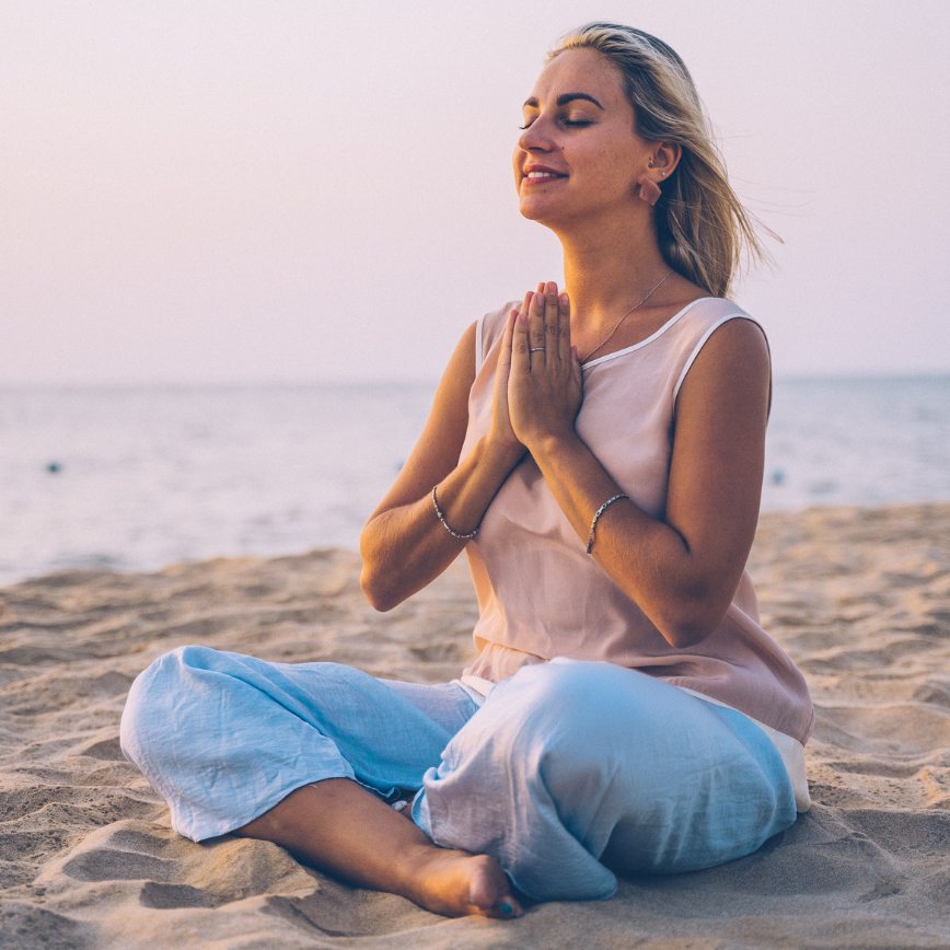 Woman sitting on beach sand meditating