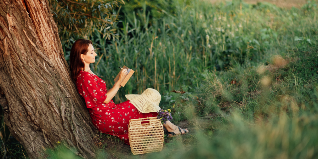 Finding your life purpose. Woman sitting under a tree doing some self-reflection writing